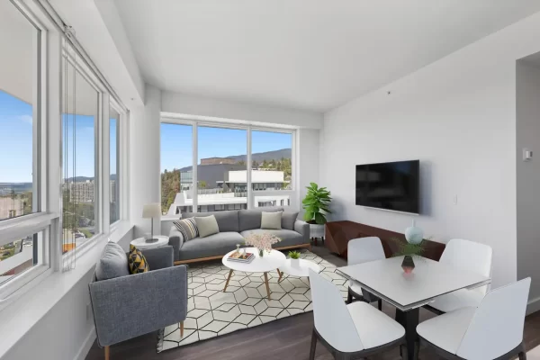 Bright, open-concept living and dining room in a West Vancouver rental apartment, featuring floor-to-ceiling windows with expansive views of the North Shore mountains.